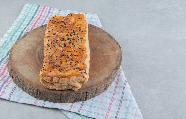 Stuffed pastry with sesame seeds on wood piece. 