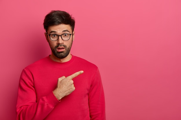 Free photo stunned bearded young man shows unbelievable presentation