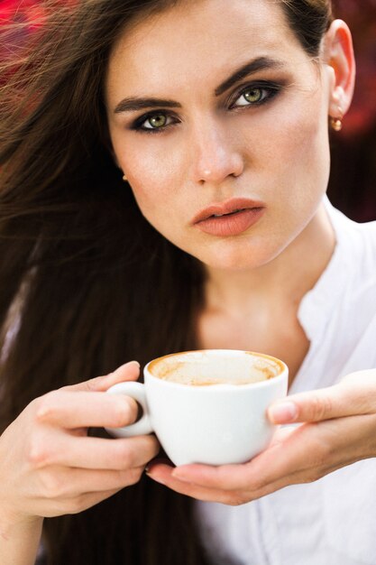 Stunning green-eyed woman sits before red flowers