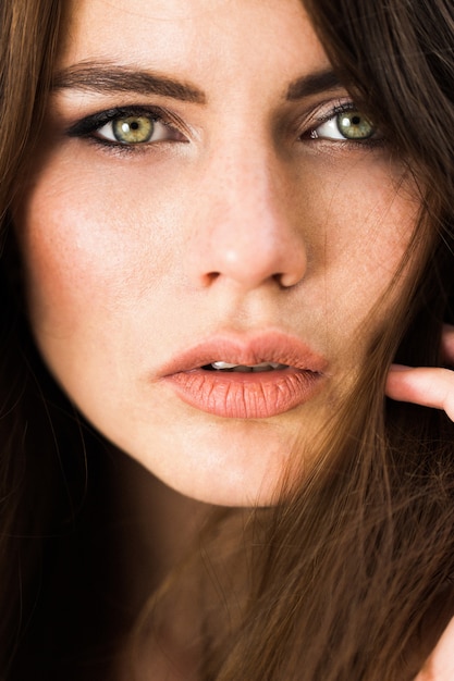 Stunning green-eyed woman sits before red flowers