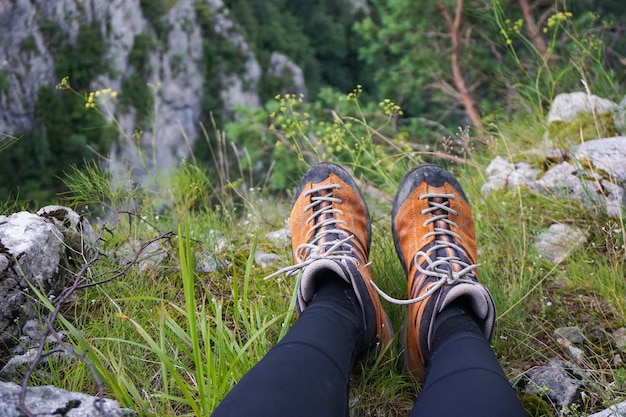 Stunning shot of a person sitting on a terrain of grass rocks and flowers in a camping ground