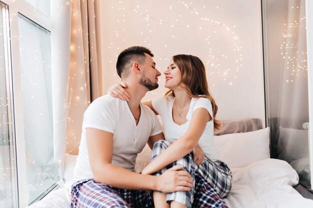 Stunning white woman looking at husband with love. Blissful female model expressing positive emotions in morning with boyfriend.