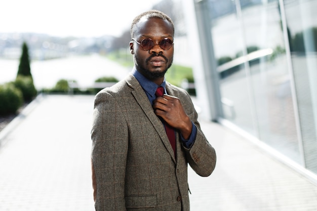 Stylish African American black businessman in round sunglasses poses