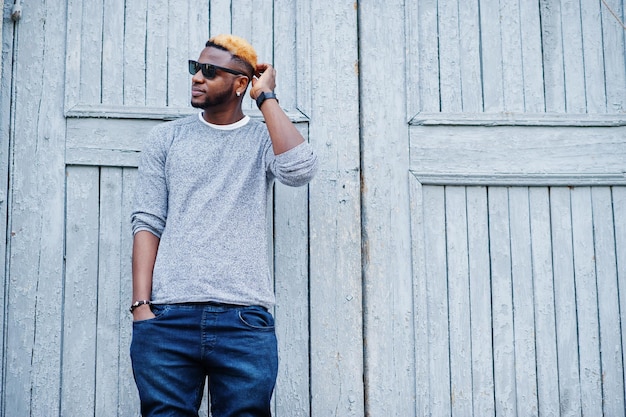 Stylish african american boy on gray sweater and black sunglasses posed on street Fashionable black guy