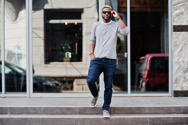 Free photo stylish african american boy on gray sweater and black sunglasses posed at street fashionable black guy