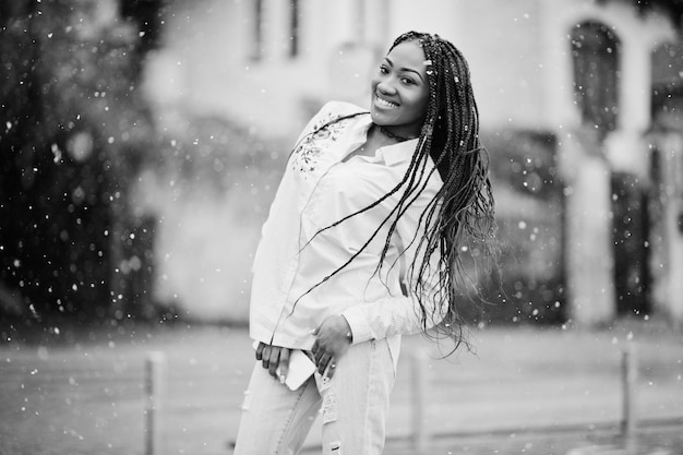 Stylish african american girl with dreads holding mobile phone at hand outdoor snowy weather