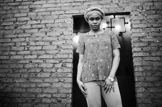 Free Photo stylish african woman in red shirt and hat posed against brick wall