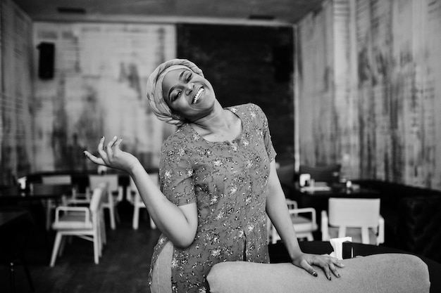 Stylish african woman in red shirt and hat posed indoor cafe