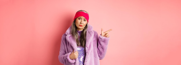 Free photo stylish asian lady with grey hair wearing trendy fakefur coat and headband complaining on something