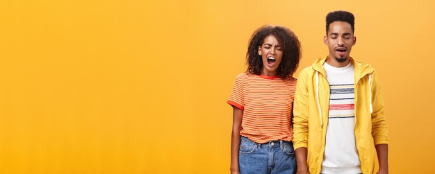 Free Photo stylish and attractive brother and sister over orange background yawning with closed eyes and tired