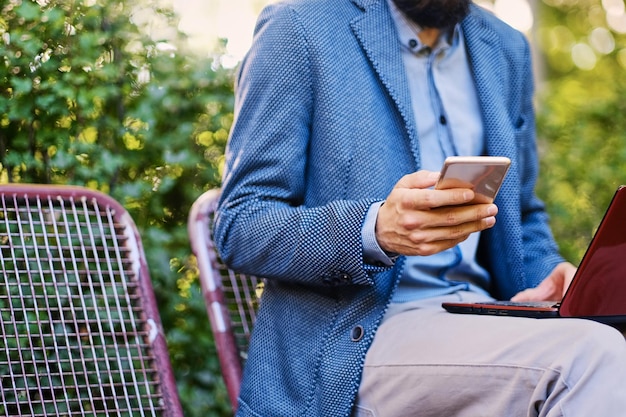 Free photo stylish bearded male in a blue jacket using smartphone.