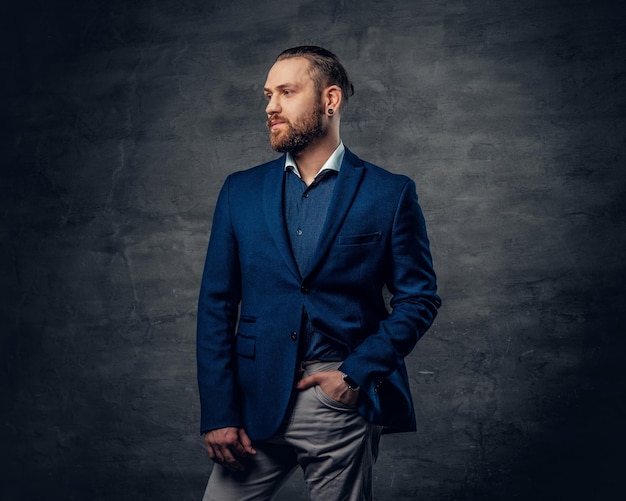 A stylish bearded male dressed in a suit and sunglasses over dark grey background.