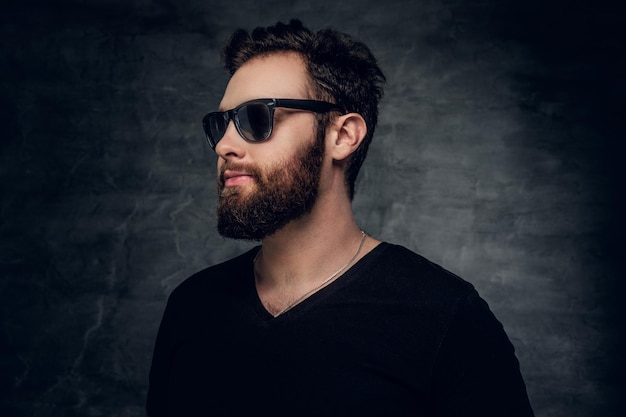 Stylish bearded male in sunglasses over grey background.