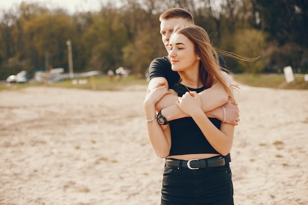 A stylish and beautiful couple in black clothes spends a good time on the beach