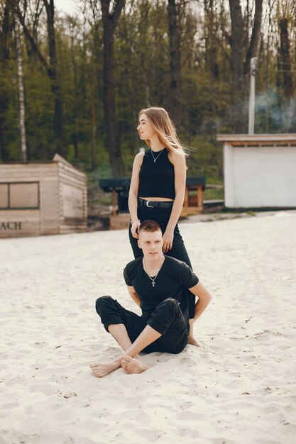 A stylish and beautiful couple in black clothes spends a good time on the beach