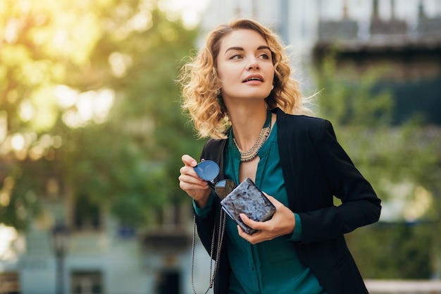 Free Photo stylish beautiful woman in jeans and jacket walking in street with little purse, elegant style, spring fashion trends