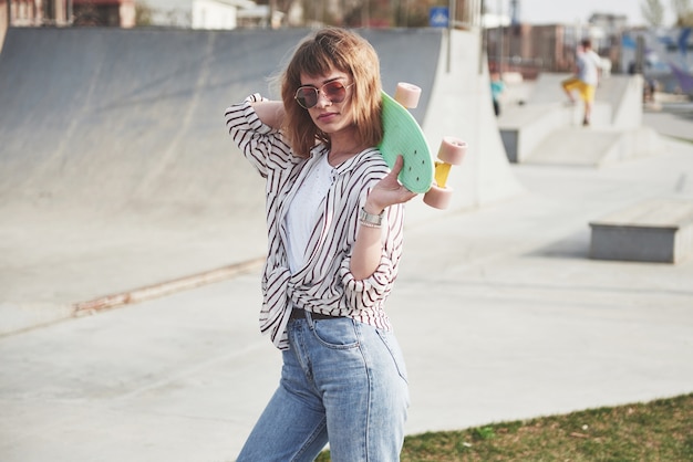 Stylish beautiful young woman with a skateboard, on a beautiful summer sunny day.