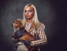 Free photo a stylish blonde female dressed in old fashioned jacket holds a red badger dog.