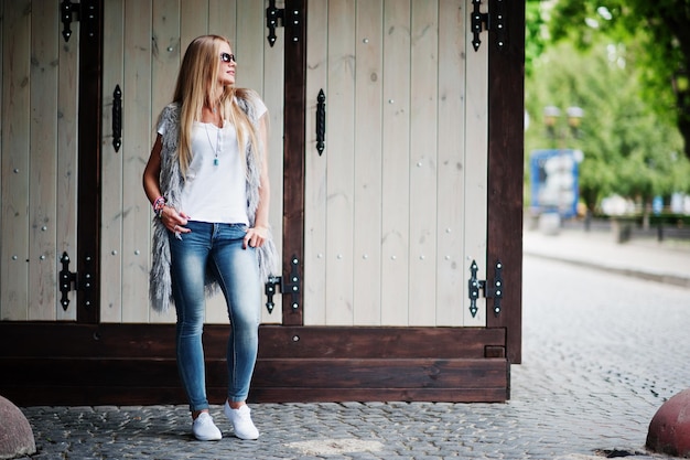 Free photo stylish blonde woman wear at jeans and girl sleeveless with white shirt against street