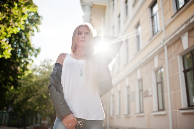 Free photo stylish blonde woman wear at jeans sunglasses and jacket posed at street on sunshine fashion urban model portrait