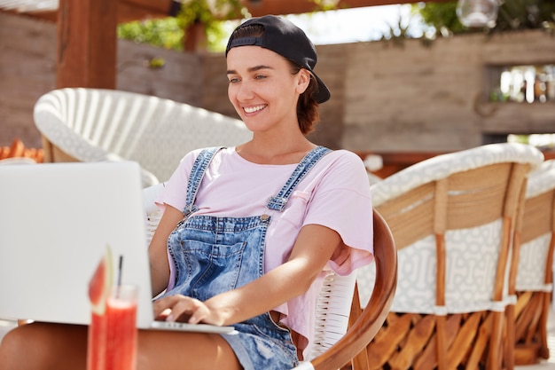 Stylish blue eyed beautiful female freelancer checks email on laptop computer, uses application on modern device