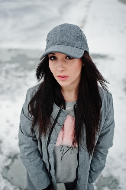 Stylish brunette girl in gray cap casual street style on winter day