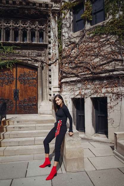 stylish brunette standing next to the entance to a building