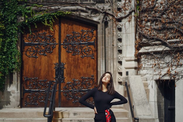 stylish brunette standing next to the entance to a building