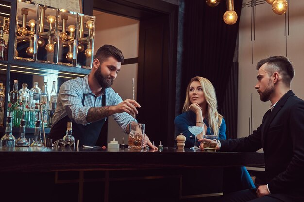 Stylish brutal bartender serves an attractive couple who spend an evening on a date.