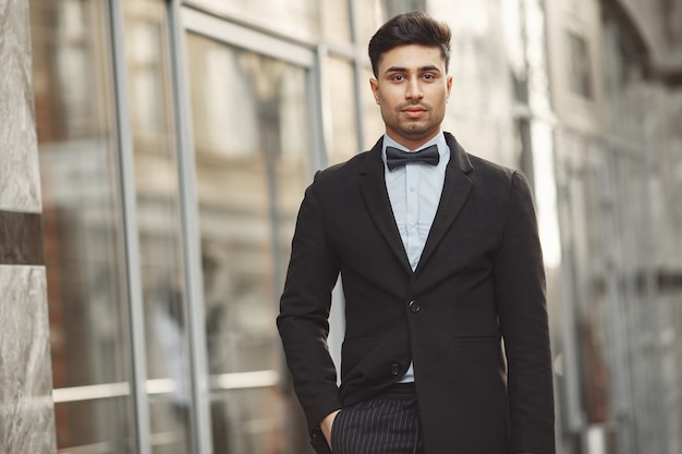 Stylish businessman in a black suit standing outside