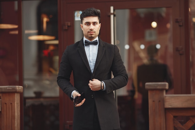 Stylish businessman in a black suit standing outside