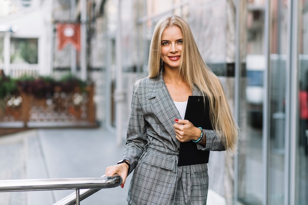 Stylish businesswoman with clipboard in city