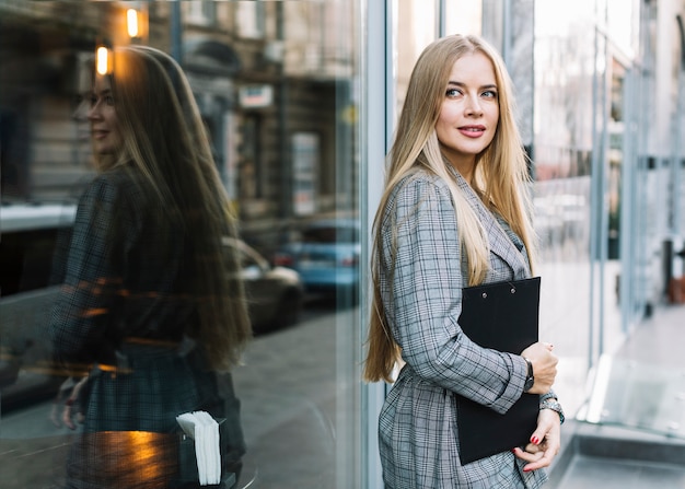 Stylish businesswoman with clipboard in city