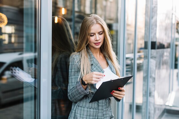 Stylish businesswoman with clipboard in city