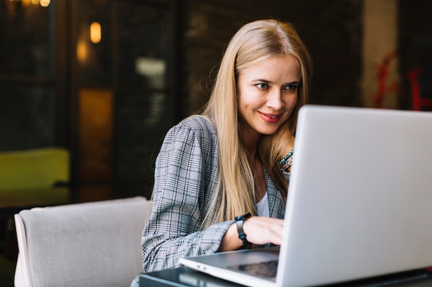 Free photo stylish businesswoman with laptop in cosy coffee shop