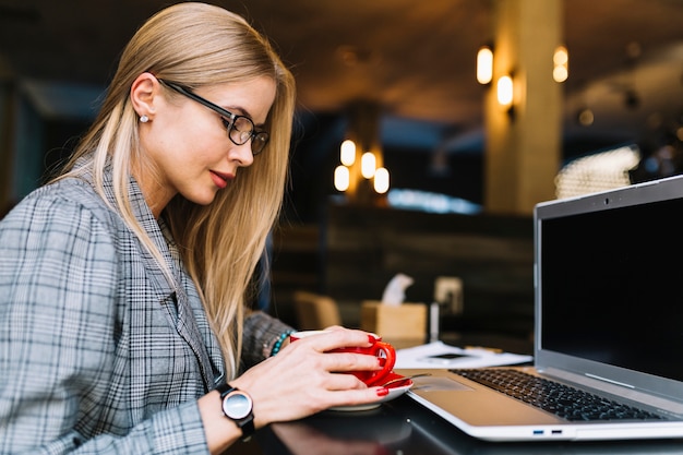 Free photo stylish businesswoman with laptop in cosy coffee shop