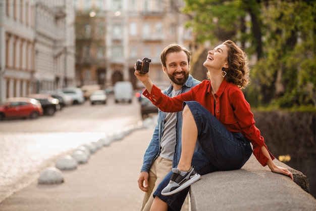 Free photo stylish couple in love sitting in street on romantic trip, taking photo