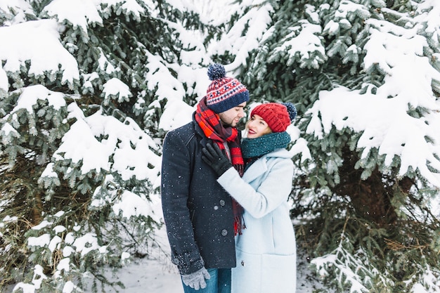 Stylish couple standing in snowy park