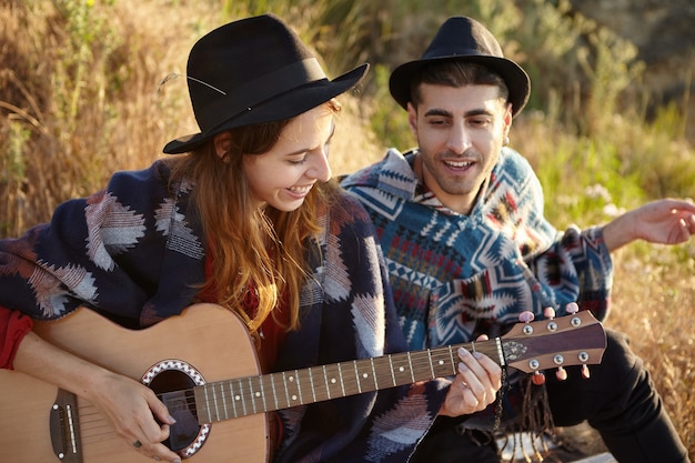 Free Photo stylish couple with guitar on field