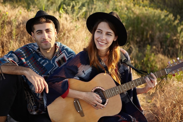 Free photo stylish couple with guitar on field