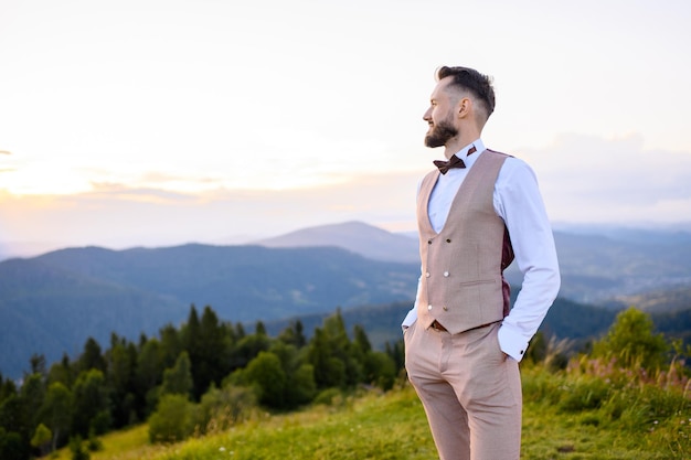 Stylish fiance posing on top enjoying view on mountains