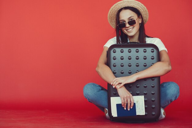 Stylish girl posing with travel equipment on a red wall