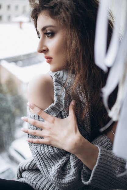 The stylish girl sitting on the window-sill