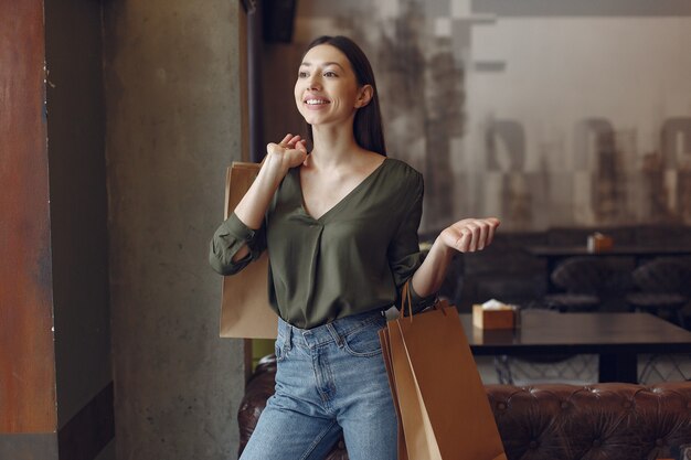 Stylish girl standing in a cafe with shopping bags