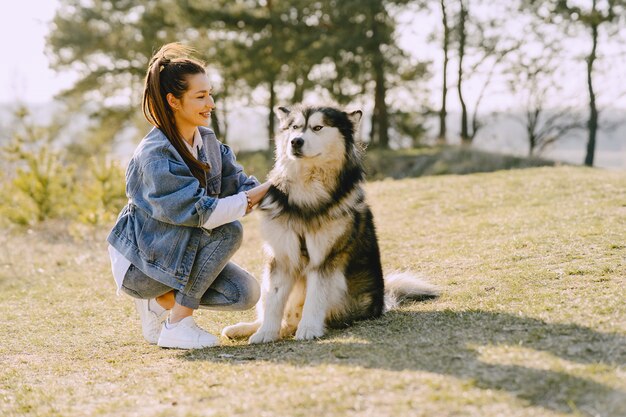 Stylish girl in a sunny field with a dog