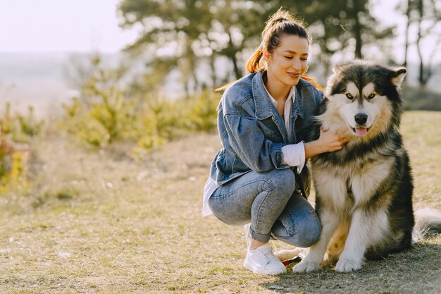 Stylish girl in a sunny field with a dog