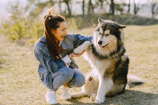 Stylish girl in a sunny field with a dog