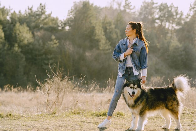 Stylish girl in a sunny field with a dog