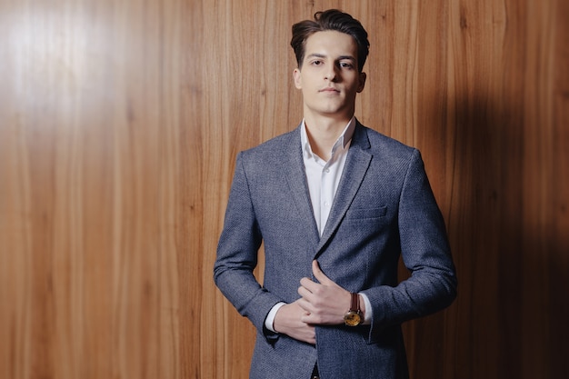 Stylish guy in jacket at office on simple wooden surface