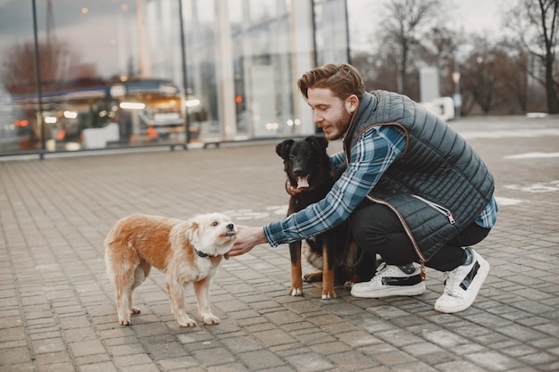 Free Photo stylish guy playing with a dogs. man in autumn city.